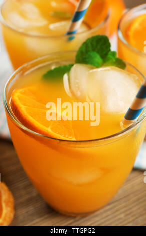 Köstliche tangerine Cocktails mit Eis, Minze und Strohhalme auf einen hölzernen Tisch serviert, in der Nähe Stockfoto