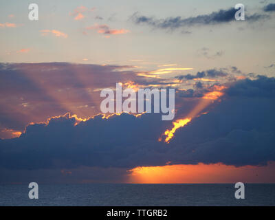 Die Majestät des Sonnenlichthimmels, die durch die Sturmwolken über dem Ozean schimmern, schöner und dramatischer Sonnenaufgang. Stockfoto