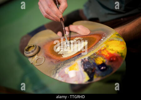 Mittelteil der Mann mit Aquarellfarbe Palette in der Werkstatt Stockfoto