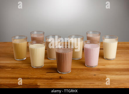 Gläser für die verschiedenen Arten von bunten Milchshake auf einer hölzernen Tischplatte Stockfoto