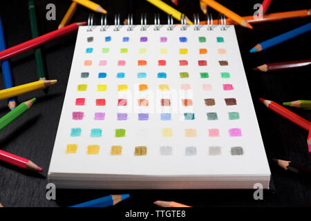 Palette von Farben in einem Skizzenbuch und farbigen Aquarellstifte. Stockfoto