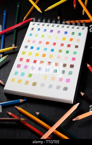 Palette von Farben in einem Skizzenbuch und farbigen Aquarellstifte. Stockfoto