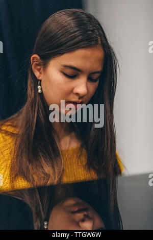 Junge Frau auf dem Klavier zu spielen. Ihr Spiegelbild in Schwarz piano Oberfläche. Stockfoto