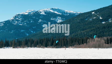 Zwei Personen kiteski auf einem zugefrorenen See an einem sonnigen Wintertag in Whistler Stockfoto