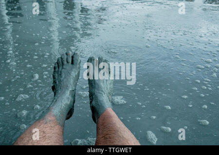 POV der Füße beschichtet im Schlamm nach eingetaucht in ein Schlammbad in Copahue. Stockfoto