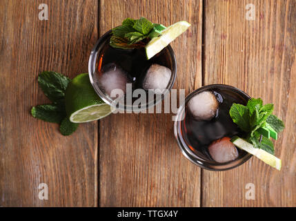 Zwei Gläser Cola mit Eis, Minze und Limette auf Holztisch, Hintergrund, Ansicht von oben Stockfoto