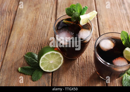 Zwei Gläser Cola mit Eis, Minze und Limette auf hölzernen Tisch Hintergrund Stockfoto