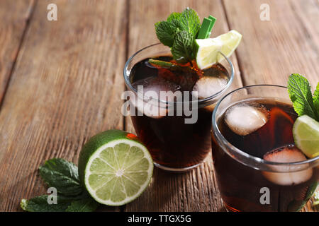 Zwei Gläser Cola mit Eis, Minze und Limette auf hölzernen Tisch Hintergrund Stockfoto