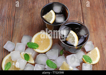 Zwei Gläser Cola mit Eiswürfeln aus Eis und Zitrone auf hölzernen Tisch Hintergrund Stockfoto