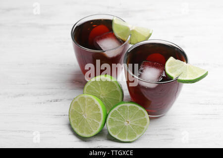 Zwei Gläser Cola mit Eis, Minze und Limette auf weissem Holztisch Hintergrund Stockfoto