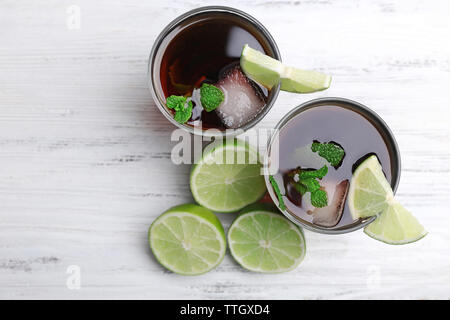 Zwei Gläser Cola mit Eis, Minze und Limette auf weissem Holztisch Hintergrund Stockfoto
