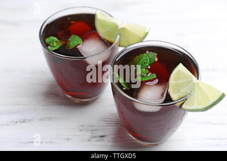 Zwei Gläser Cola mit Eis, Minze und Limette auf weissem Holztisch Hintergrund Stockfoto