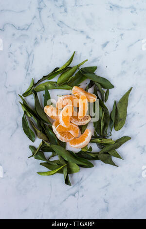 Ansicht von oben von geschälten Mandarinen Schichten mit Blättern auf Marmor tisch Stockfoto