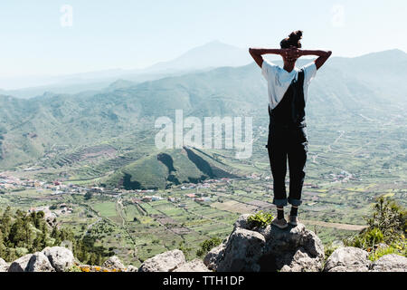 Zurück Blick auf Frau steht auf Rock mit den Teide im Hintergrund Stockfoto