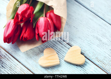 Rote Tulpen Blumenstrauß in einer Papiertüte mit einem Geschenk Box auf einem hellblauen Tabelle Stockfoto