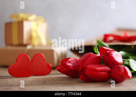 Rote Tulpen mit dekorativen Herzen auf einen hölzernen Tisch, in der Nähe Stockfoto
