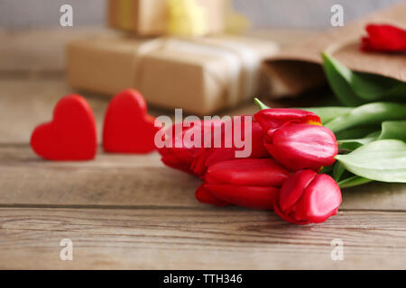 Rote Tulpen mit dekorativen Herzen auf einen hölzernen Tisch, in der Nähe Stockfoto