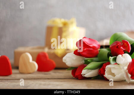 Blumenstrauß aus roten und weißen Tulpen in einer Papiertüte auf einem Holztisch, Nahaufnahme Stockfoto