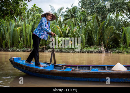 Eine Frau, die Paddel ein Boot entlang eines Flusses in Vietnam Mekong Delta Stockfoto