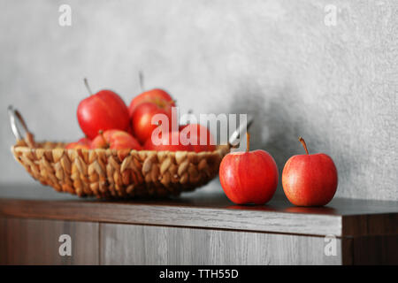 Wicker Fach mit reifen Äpfeln auf hölzernen Tisch Stockfoto