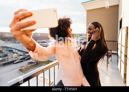 Geschäftsfrau, Smart Phone, während bei weiblichen Kollegen im Hotel Balkon suchen Stockfoto