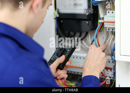 Junger Elektriker die Messung der Spannung in der Sicherungsplatine Stockfoto