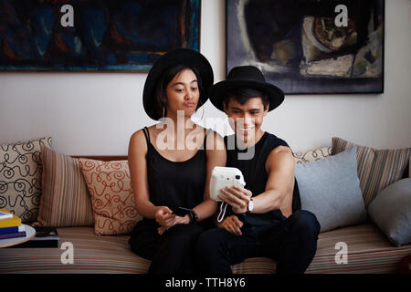 Frau, Lippen kräuseln, während des Gesprächs Selfie mit Mann durch Sofortbild-Kamera im Wohnzimmer Stockfoto
