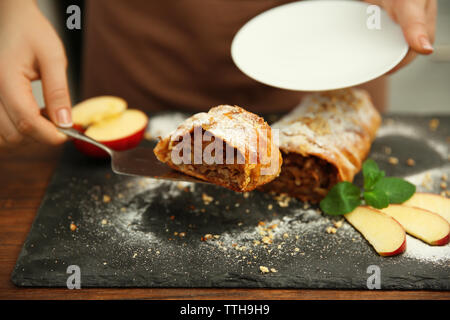 Frau, ein Stück Apfel Roll auf Untertasse Stockfoto