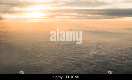 Antenne reisen. Wunderbare Sicht auf den Himmel und Wolken mit der Dämmerung von oben, wie durch ein Flugzeug Fenster gesehen. Morgennebel. Fliegen in der Dämmerung Stockfoto