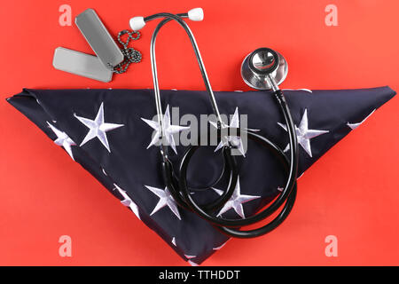 Stethoskop mit Token und Stars der USA-Flagge auf rotem Hintergrund Stockfoto