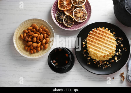 Frische Waffeln mit Honig und getrockneten Orangen auf Holz- Hintergrund Stockfoto