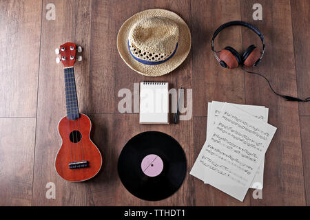 Gitarre, Kopfhörer, Musik, Blätter und Stroh Hut auf Holz- Oberfläche, Ansicht von oben Stockfoto
