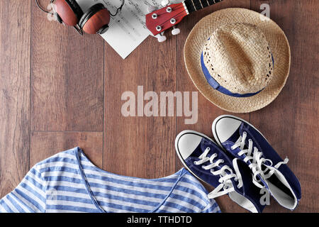 Gitarre, Kopfhörer, Musik Bettwäsche und Kleidung auf Holz- Oberfläche, Ansicht von oben Stockfoto