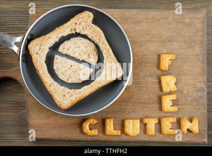 Das Brot in Scheiben schneiden, in einer Pfanne mit Glutenfreien text auf Holz- Hintergrund Stockfoto