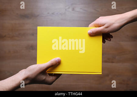 Männliche und weibliche Hände halten Buch über Holz- Hintergrund. Stockfoto
