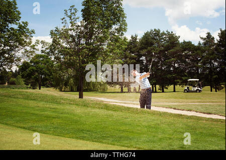 Junger Mann Schwingen Golf Club im Feld Stockfoto