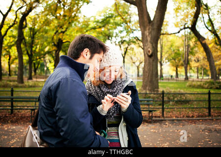 Junges Paar mit Phone beim Stehen in Central Park Stockfoto