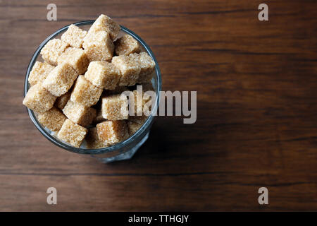 Highball Glas mit braunen Klumpen Zucker auf hölzernen Tisch Stockfoto