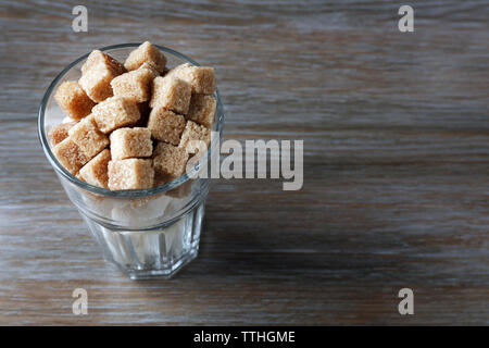 Highball Glas mit braunen und weißen Klumpen Zucker auf hölzernen Tisch Stockfoto