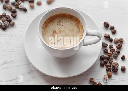 Tasse Kaffee und Kaffeebohnen auf hellen Hintergrund Stockfoto