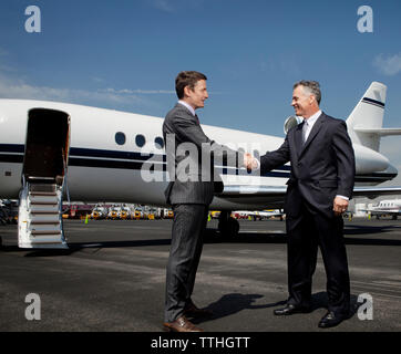 Gerne Unternehmer tun Handshake gegen Corporate Jet auf Start- und Landebahn Stockfoto