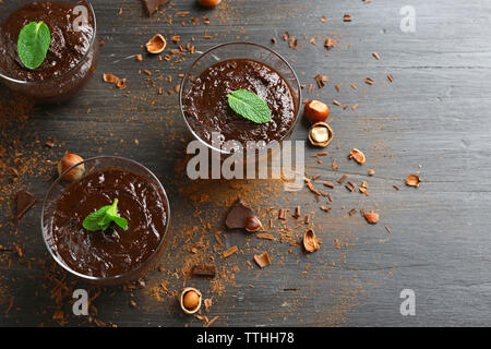 Glas Tassen Schokolade Dessert mit frischer Minze und Haselnüsse auf schwarzen Holztisch Stockfoto
