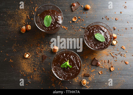 Glas Tassen Schokolade Dessert mit frischer Minze und Haselnüsse auf schwarzen Holztisch Stockfoto