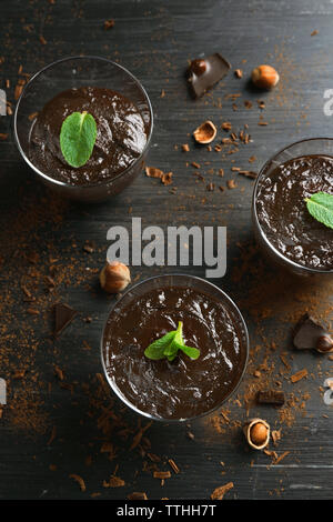 Glas Tassen Schokolade Dessert mit frischer Minze und Haselnüsse auf schwarzen Holztisch Stockfoto