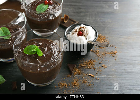 Glas Tassen Schokolade Dessert mit frischer Minze und aufgeschäumter Milch auf schwarzen Holztisch Stockfoto