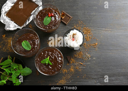 Glas Tassen Schokolade Dessert mit frischer Minze und aufgeschäumter Milch auf schwarzen Holztisch Stockfoto
