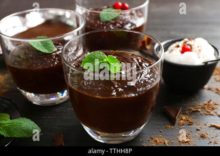 Glas Tassen Schokolade Dessert mit frischer Minze und aufgeschäumter Milch auf schwarzen Holztisch Stockfoto