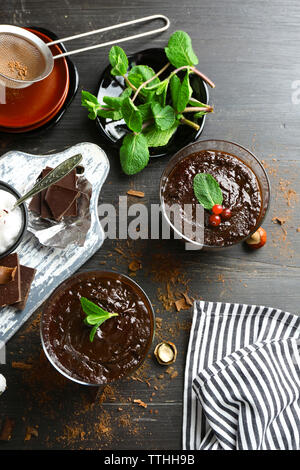 Glas Tassen Schokolade Dessert mit frischer Minze auf schwarzen Holztisch Stockfoto