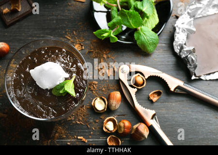Glas Tasse Schokolade Dessert mit frischer Minze und aufgeschäumter Milch auf schwarzen Holztisch Stockfoto