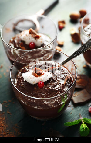 Glas Tassen Schokolade Dessert mit aufgeschäumter Milch und Preiselbeeren auf schwarzen Holztisch Stockfoto